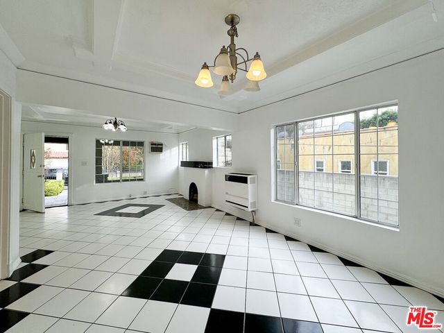 a room with a black white checkered floor with a large window and chandelier