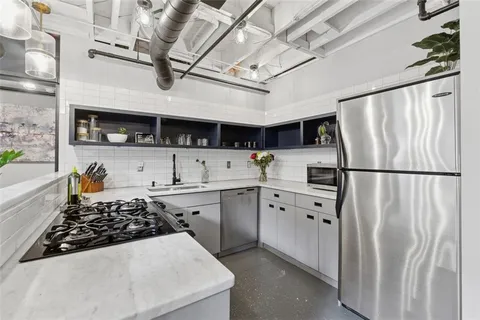 a kitchen with stainless steel appliances granite countertop a refrigerator a sink dishwasher a stove and a refrigerator with wooden floor