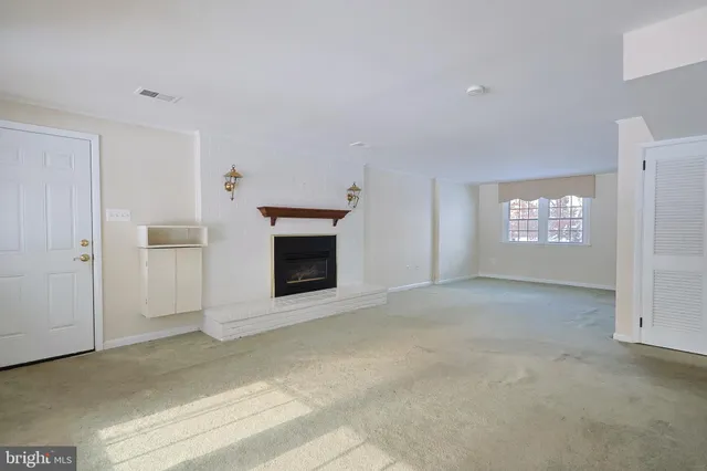 a view of an empty room with a fireplace and a window