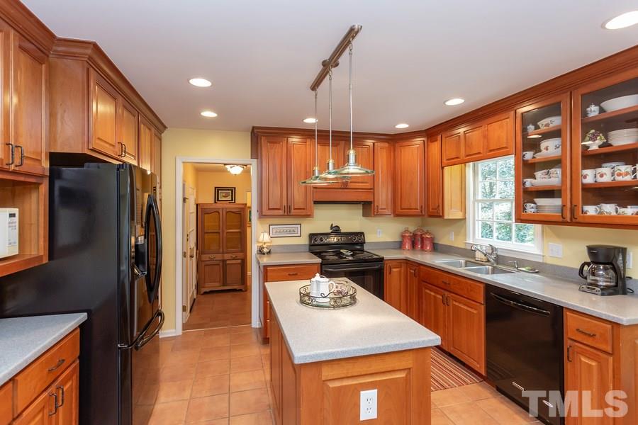 8609 Seagate Drive Raleigh, NC 27615 - Photo 10 of 28 Cook with ease in this perfect triangle with abundance of cherry cabinets, island and solid surface counter tops.