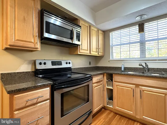 a kitchen with stainless steel appliances granite countertop white cabinets and a stove top oven