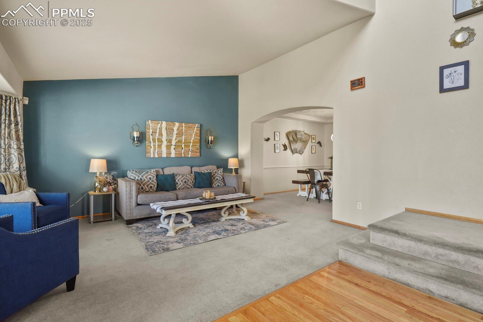 7660 Bullet Road Peyton, CO 80831 - Photo 4 of 50 Living room featuring arched walkways, carpet flooring, wood finished floors, and high vaulted ceiling