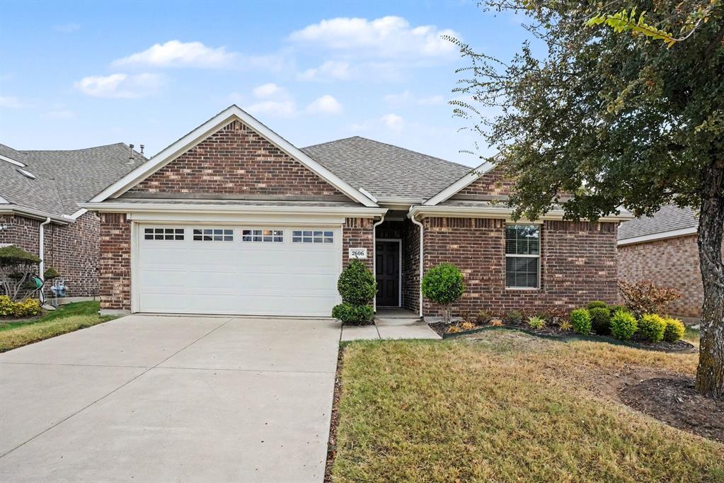 2606 Middleton Road Glenn Heights, TX 75154 - Photo 2 of 18 Brick exterior with a gabled roofline, attached garage with decorative windows, concrete driveway, and established front landscaping