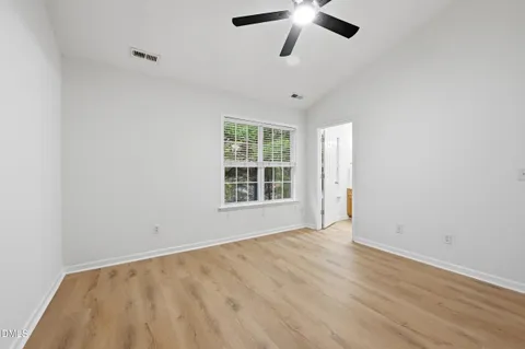 an empty room with a window and a ceiling fan