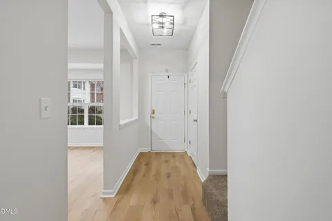 a view of a hallway with wooden floor and a bathroom