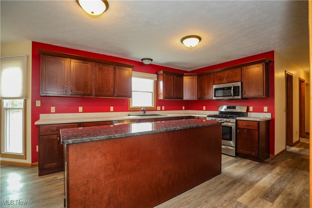 12565 Alpha Road Hiram, OH 44234 - Photo 14 of 50 Kitchen featuring a kitchen island, baseboards, appliances with stainless steel finishes, wood finished floors, and a sink