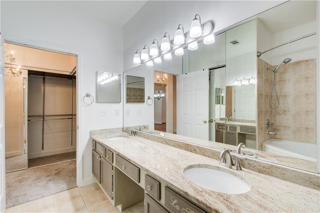 2865 Lenox Road Northeast, Unit 102 Atlanta, GA 30324 - Photo 26 of 35 a bathroom with a granite countertop sink a large mirror and a shower