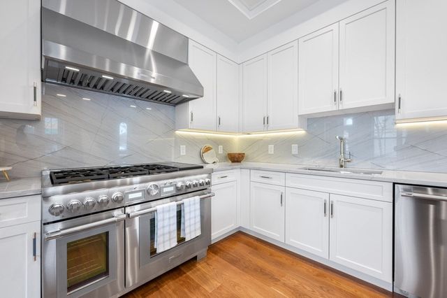 a kitchen with granite countertop stainless steel appliances a sink stove and cabinets