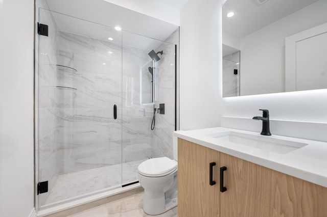 a bathroom with a granite countertop sink a toilet and a shower
