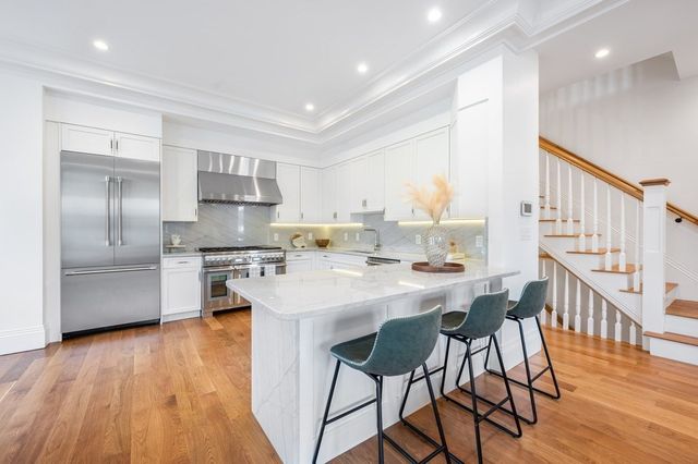 a living room with stainless steel appliances kitchen island granite countertop a table chairs and a refrigerator