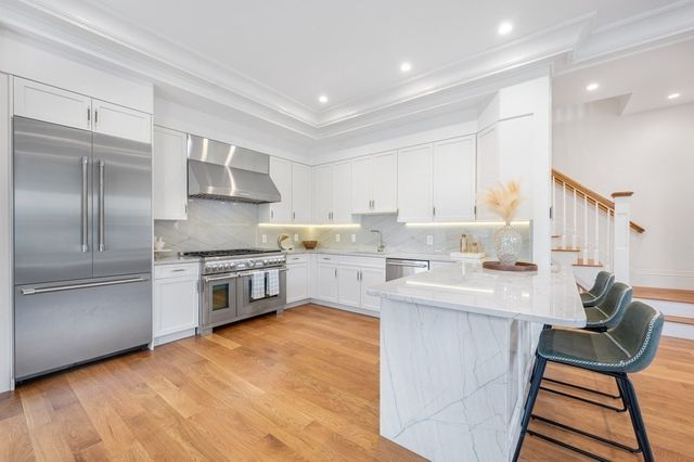 a kitchen with stainless steel appliances kitchen island granite countertop a stove a sink a refrigerator and cabinets