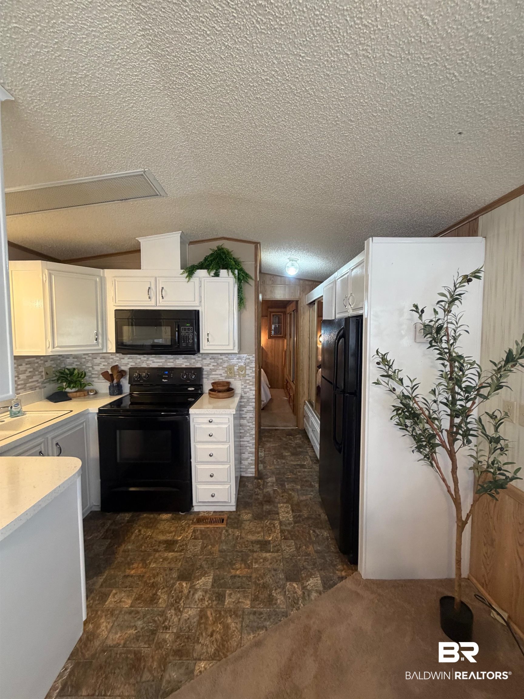 685 Escambia Loop Lillian, AL 36549 - Photo 10 of 43 Kitchen featuring stone finish floors, white cabinets, black appliances, light countertops, and a textured ceiling