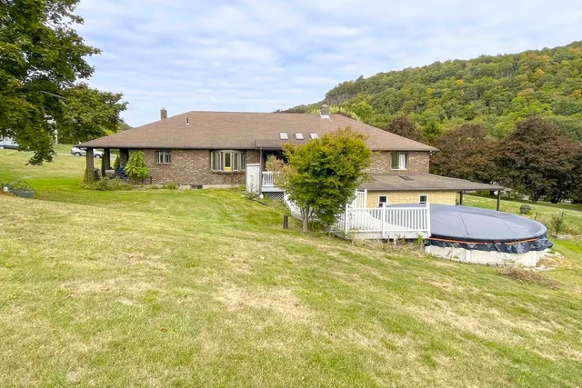 a white house with a large pool and lawn chairs under an umbrella