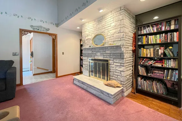 a living room with bookshelf and a fireplace