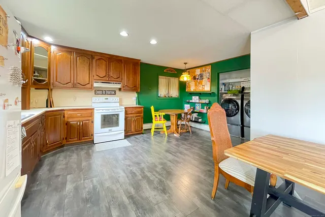 a living room with stainless steel appliances furniture wooden floor and a kitchen view