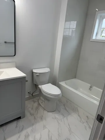 a white toilet sitting next to a bathroom sink and vanity