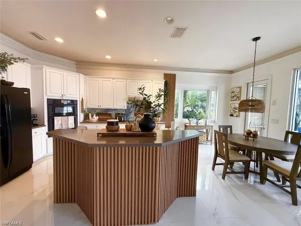 a kitchen with stainless steel appliances kitchen island granite countertop a table chairs and a refrigerator