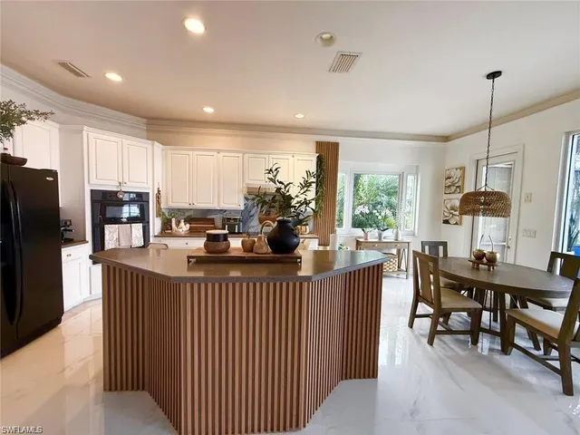 a kitchen with stainless steel appliances kitchen island granite countertop a table chairs and a refrigerator