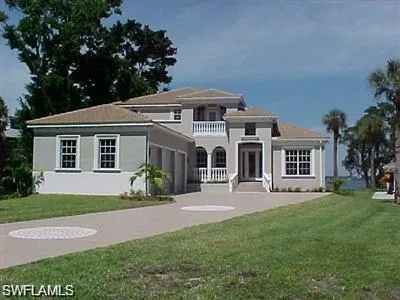 a front view of a house with a garden and trees