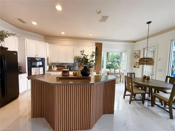 a kitchen with stainless steel appliances kitchen island granite countertop a table chairs and a refrigerator