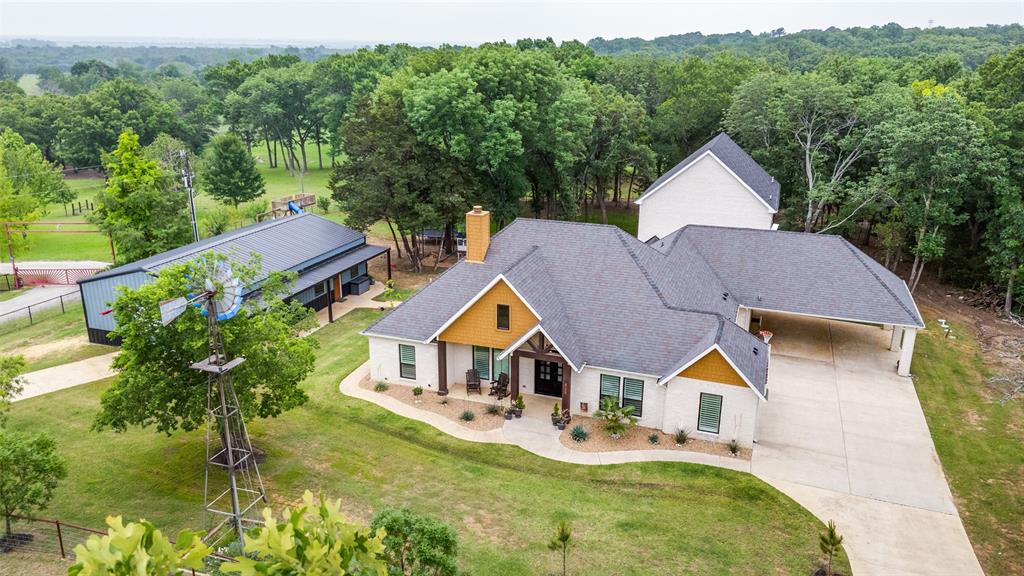 586 Rustic Oaks Road Combine, TX 75159 - Photo 37 of 39 Contemporary residence featuring a light-colored exterior with wood accents, a covered front porch, and an attached carport