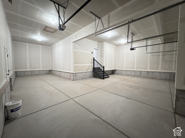 2633 Scarlet Road, Unit 259 Eagle Mountain, UT 84005 - Photo 29 of 29 Spacious garage with concrete flooring, exposed ceiling joists, and a built-in staircase with black railing