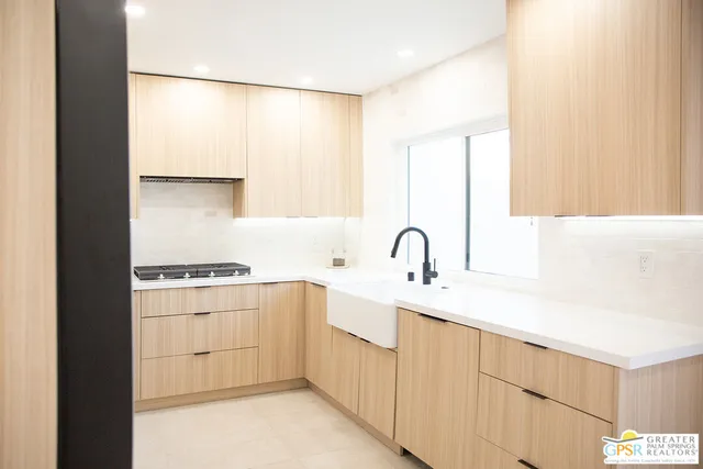 a kitchen with a sink a stove and white cabinets