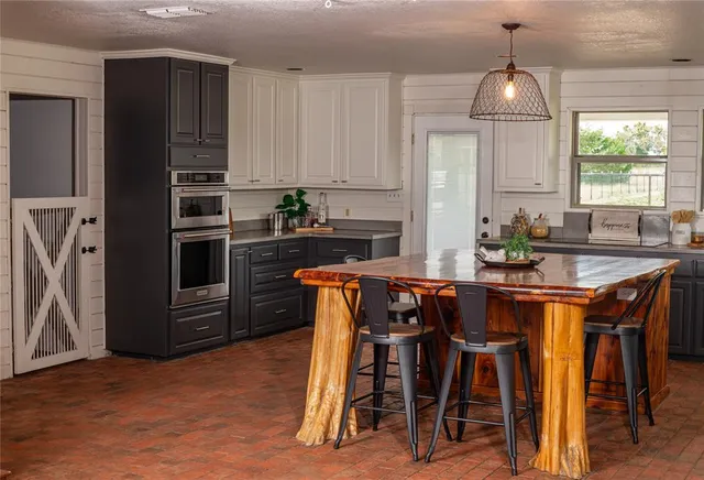 a kitchen with stainless steel appliances granite countertop a stove a refrigerator a sink a dining table and chairs with wooden floor