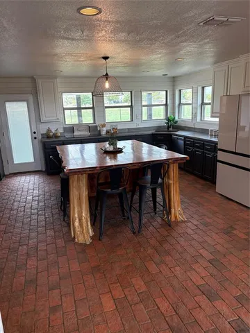 a large room with lots of wooden furniture a large window and stainless steel appliances