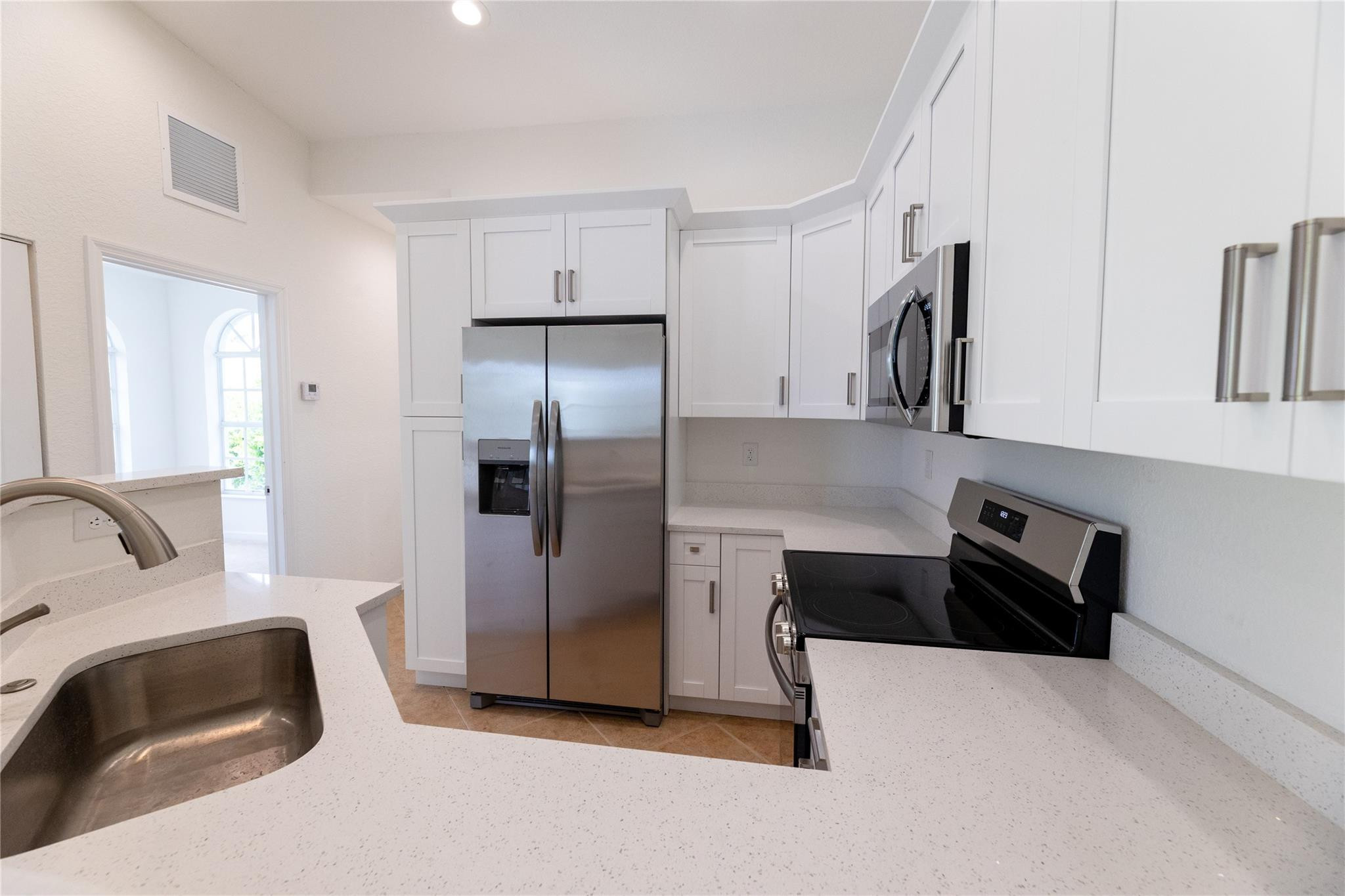 3199 Laurel Ridge Circle, Unit 3199 Riviera Beach, FL 33404 - Photo 24 of 44 a kitchen with white cabinets and stainless steel appliances