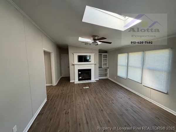 a view of an empty room with wooden floor fireplace and a window