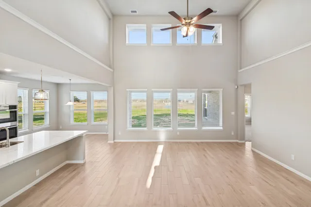 a view of an empty room with a window and kitchen view