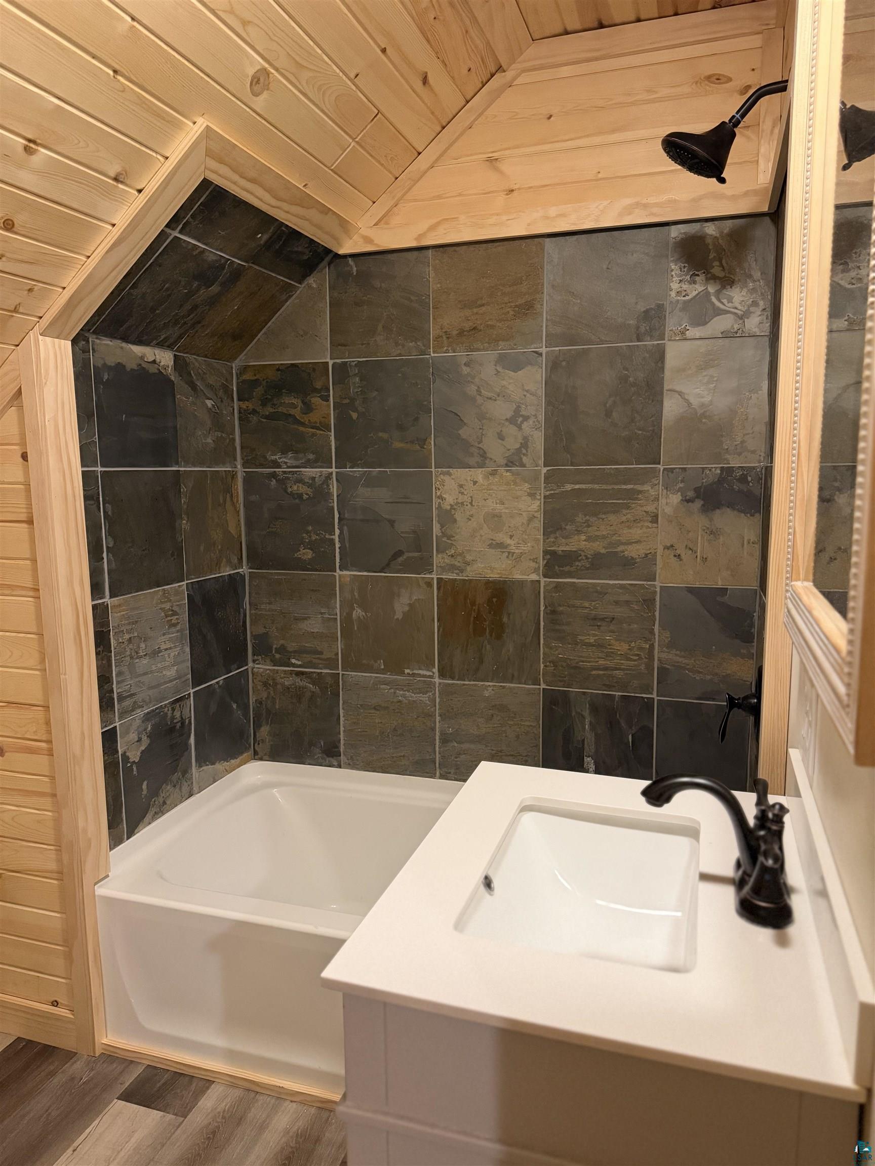 5274 Marble Lake Road Two Harbors, MN 55616 - Photo 45 of 79 Bathroom featuring a tub/shower combination with natural stone-look tile surround and a wood-paneled ceiling