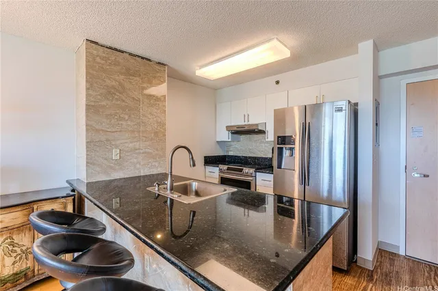 a kitchen with stainless steel appliances granite countertop a sink a stove and a refrigerator