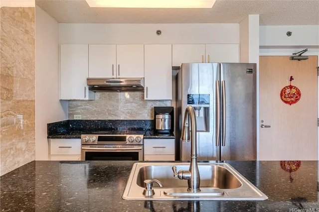 a kitchen with stainless steel appliances a refrigerator a stove a sink and white cabinets