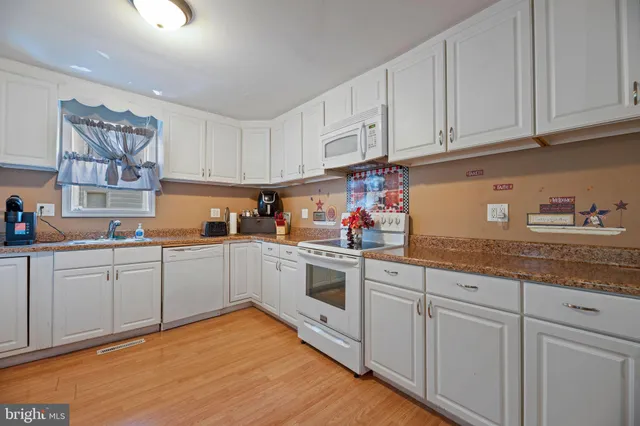 a kitchen with granite countertop white cabinets and white appliances