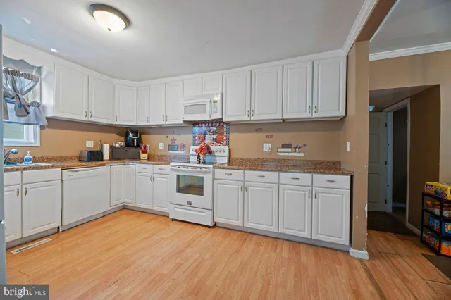 a kitchen with granite countertop white cabinets and white appliances