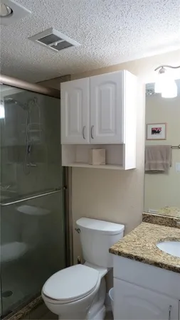 a bathroom with a granite countertop toilet and a sink