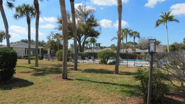 a view of a patio with couches table and chairs under an umbrella with large trees