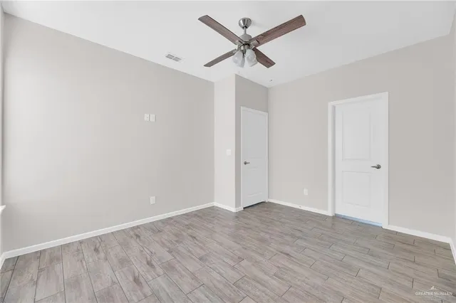 an empty room with wooden floor and ceiling fan