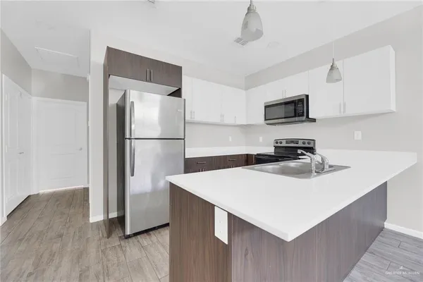 a kitchen with stainless steel appliances a sink a stove a refrigerator and cabinets