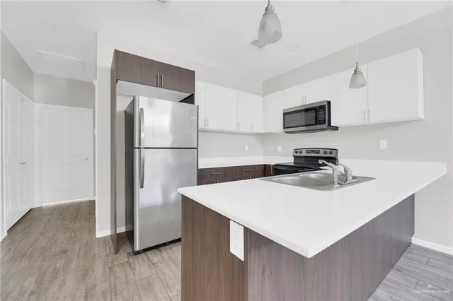 a kitchen with stainless steel appliances a sink a stove a refrigerator and cabinets