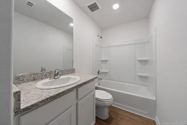 a bathroom with a granite countertop sink toilet and shower