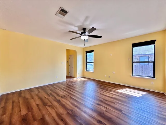 a view of an empty room with window and wooden floor
