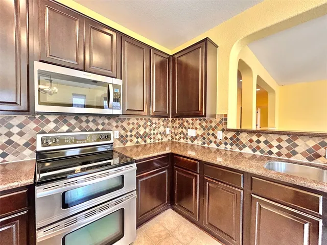 a kitchen with stainless steel appliances granite countertop a refrigerator and a stove top oven
