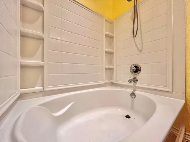 a view of an empty room with wooden floor and a ceiling fan