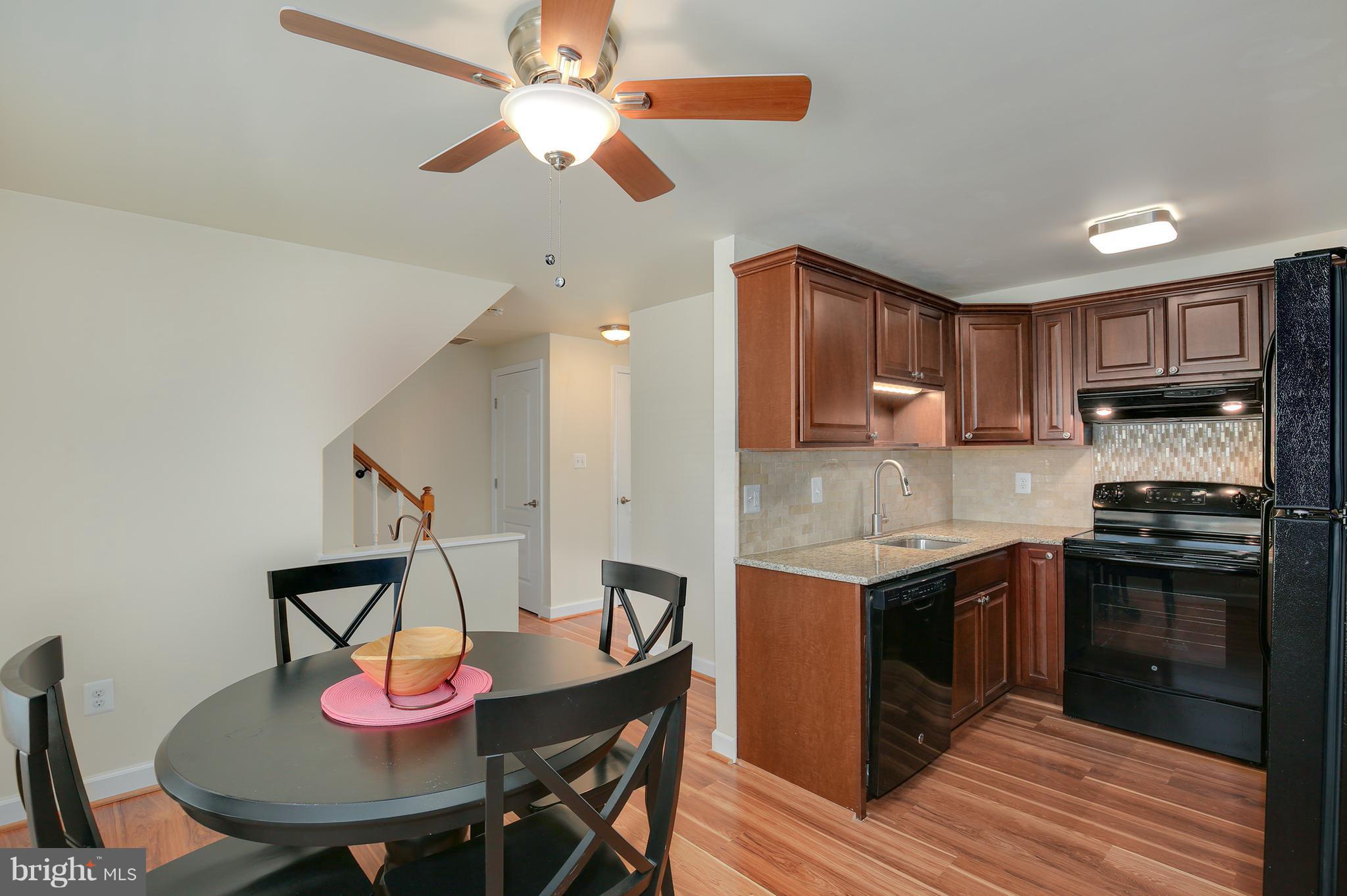 17555 Kohlhoss Road Poolesville, MD 20837 - Photo 7 of 24 a kitchen with stainless steel appliances granite countertop a stove top oven a sink a dining table and chairs with wooden floor