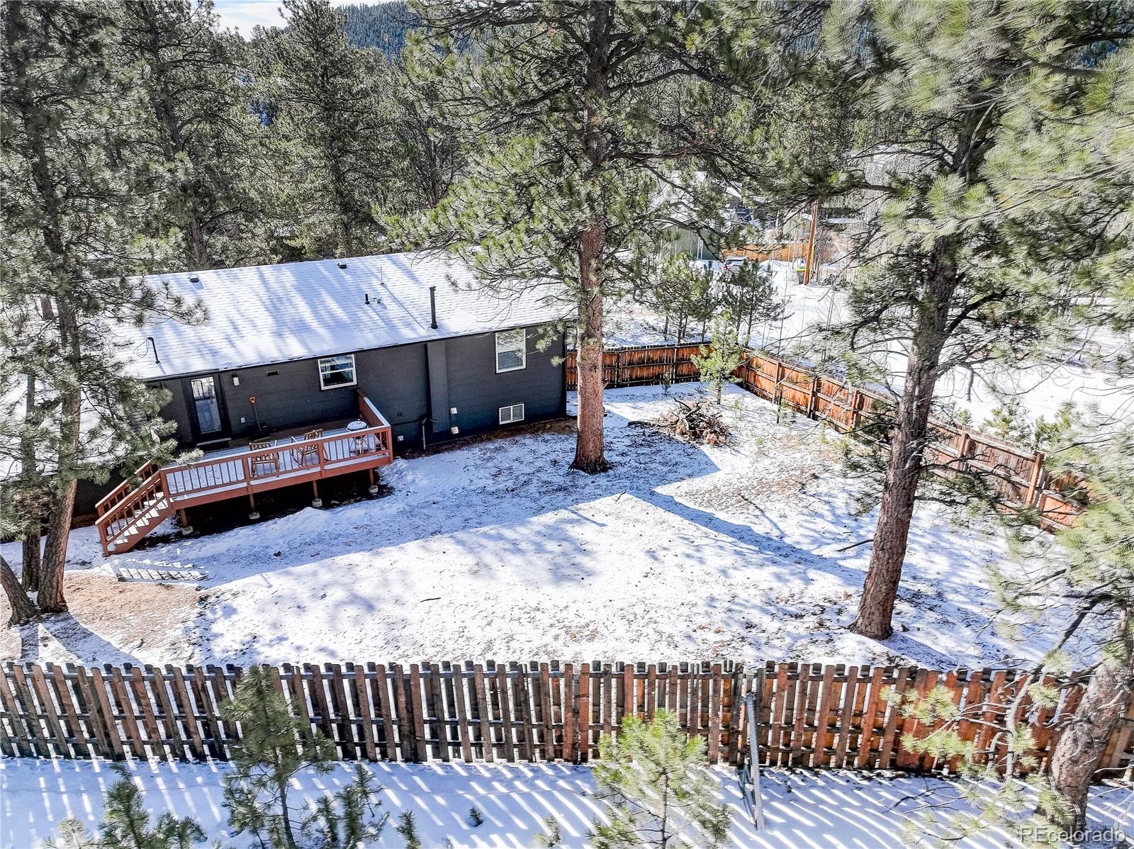 95 Fitzsimmons Road Bailey, CO 80421 - Photo 2 of 38 a backyard of a house with barbeque oven and trees