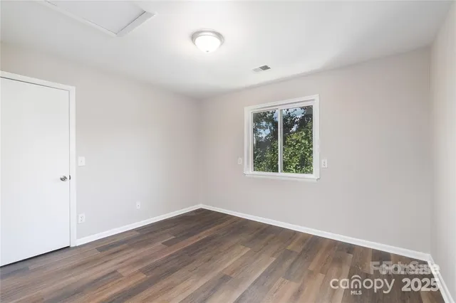 an empty room with wooden floor and window