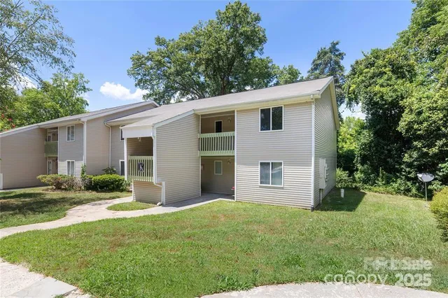 a backyard of a house with plants and large tree